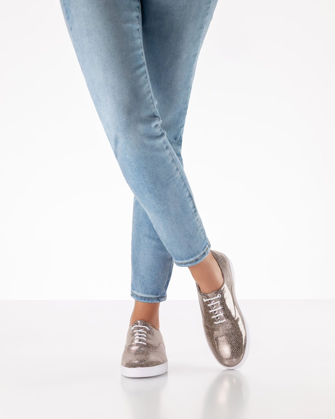 Zapatos de baile brillantes de color platino, con cordones y suela blanca, de Werner Kern, combinados con unos vaqueros claros