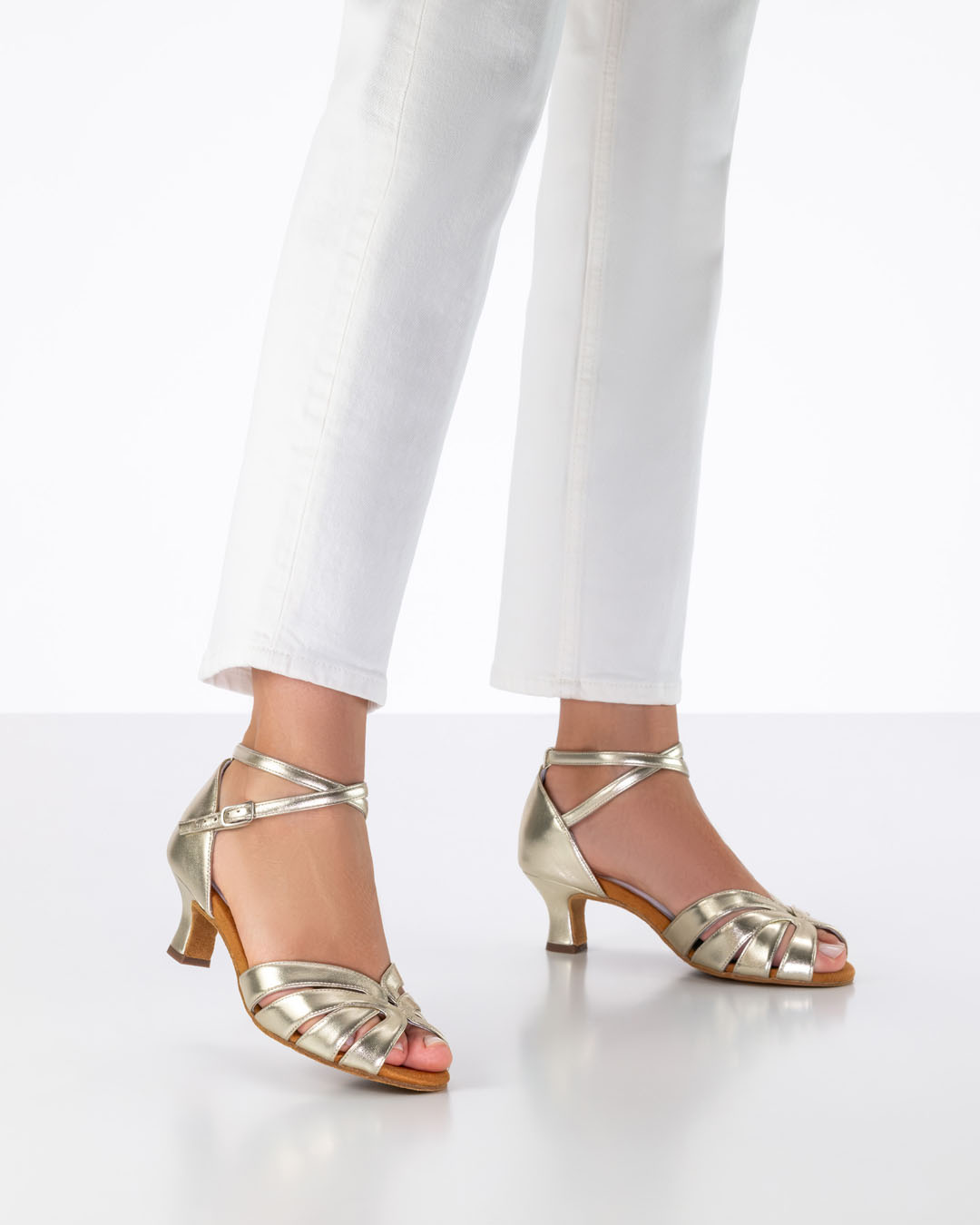 La modelo lleva vaqueros blancos y sandalias de baile doradas con tacón acampanado de 5 cm.