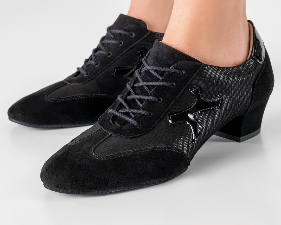 Primer plano del zapato de baile Bruni en negro brillante con detalles de zapatilla deportiva en ante.