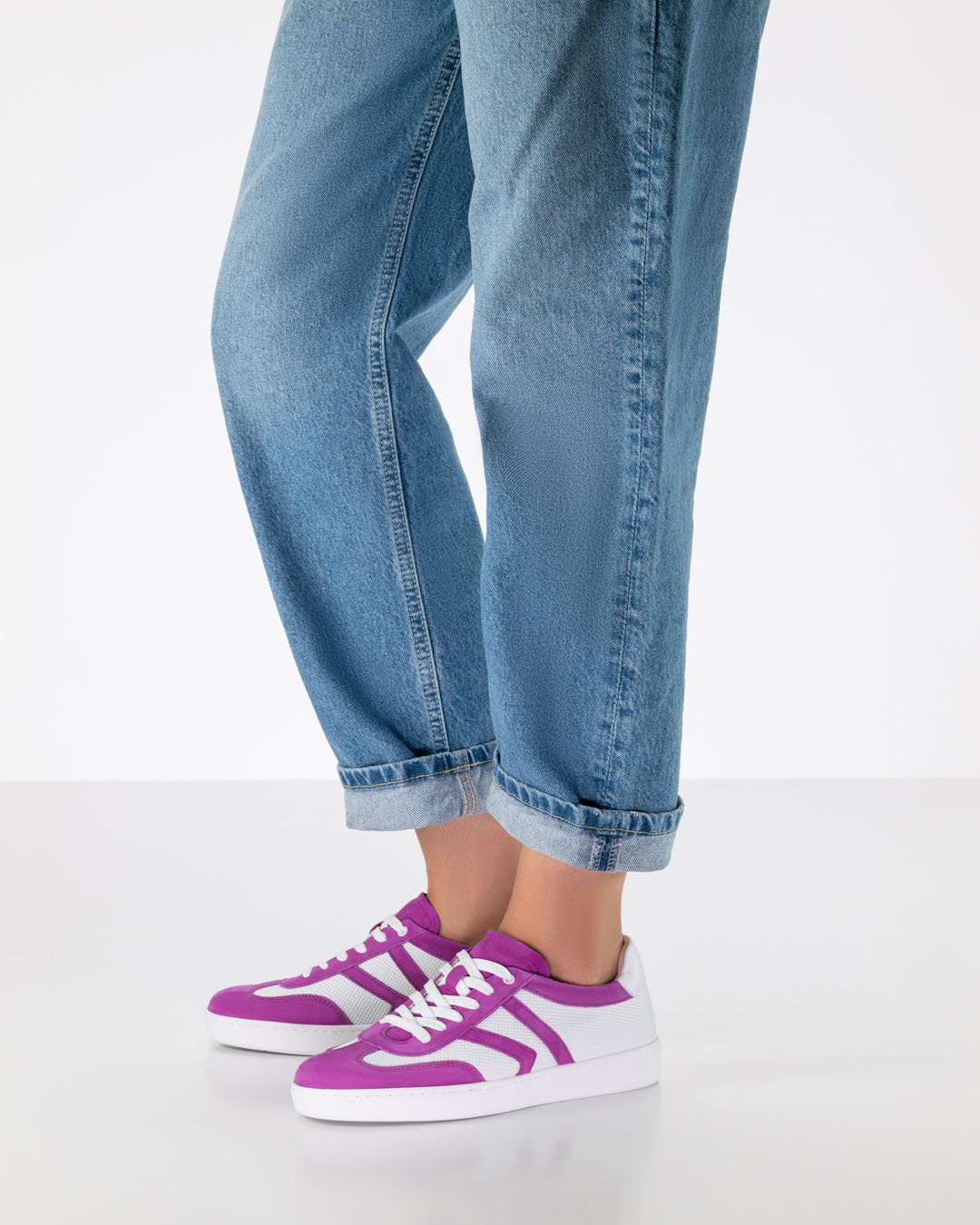 Las piernas de un modelo de zapatos de baile con vaqueros de corte desenfadado y zapatillas de baile de cuero blanco y rosa con suela de PU blanca