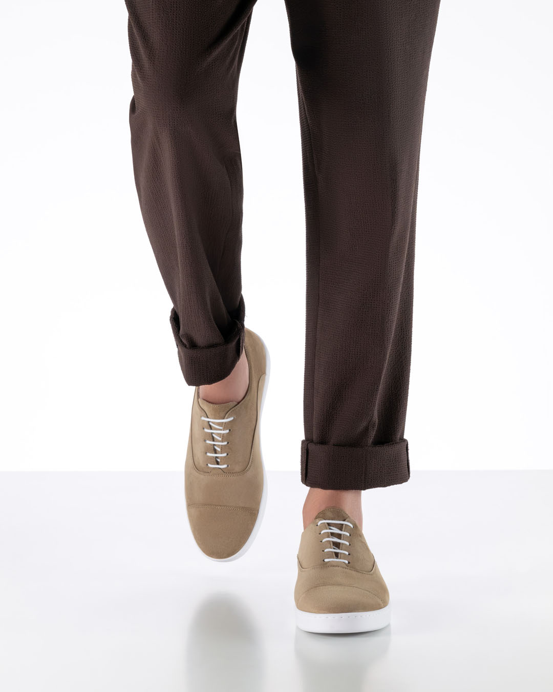 La modelo camina hacia la cámara y lleva unas zapatillas de baile de color beige claro con suela plana blanca tipo zapatilla deportiva.